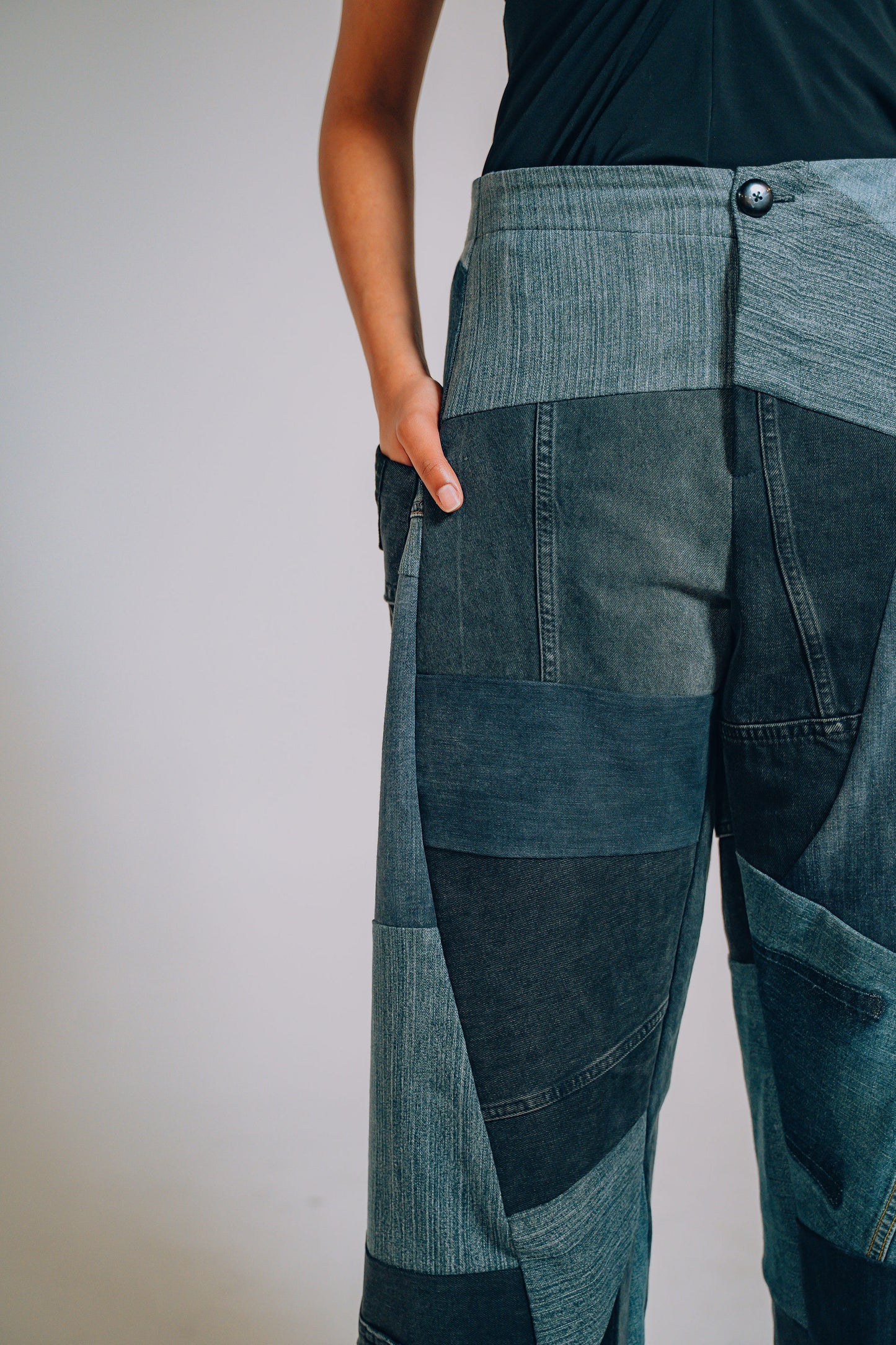 Patchwork denim pants worn by a person on a plain background