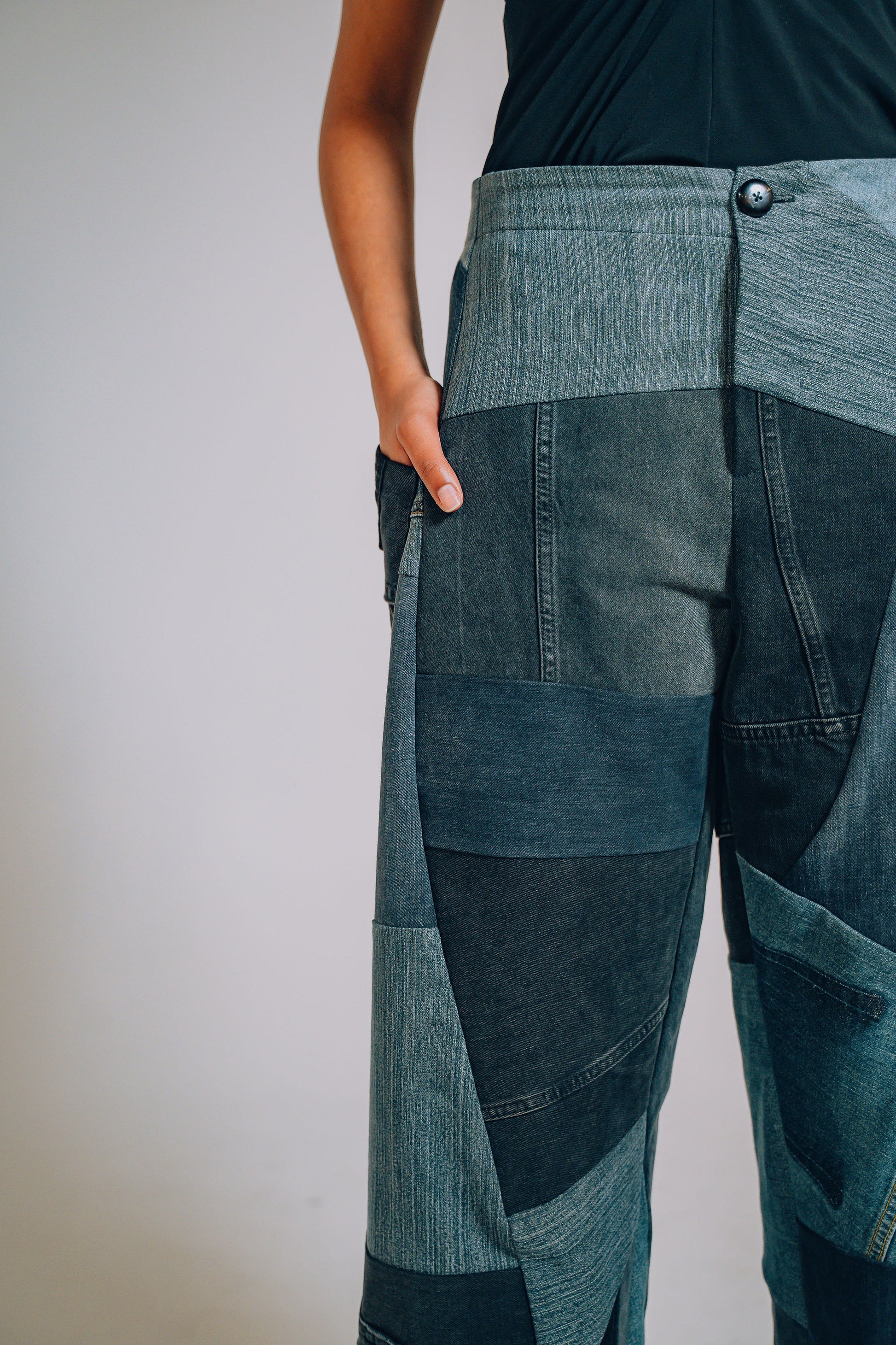 Patchwork denim pants worn by a person on a plain background