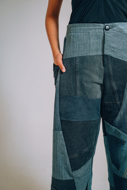 Patchwork denim pants worn by a person on a plain background