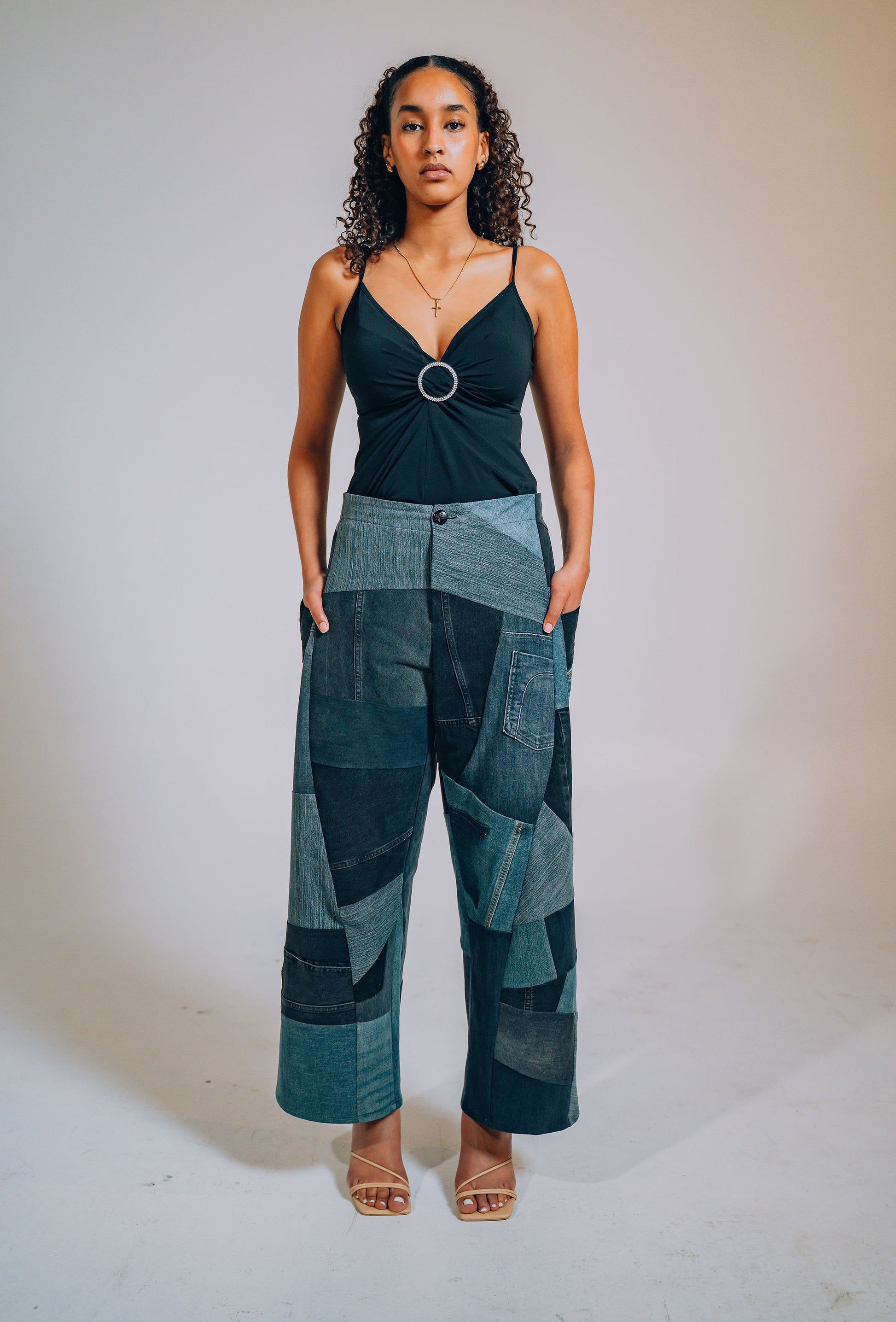 Woman wearing blue and black patchwork pants outfit against a plain background