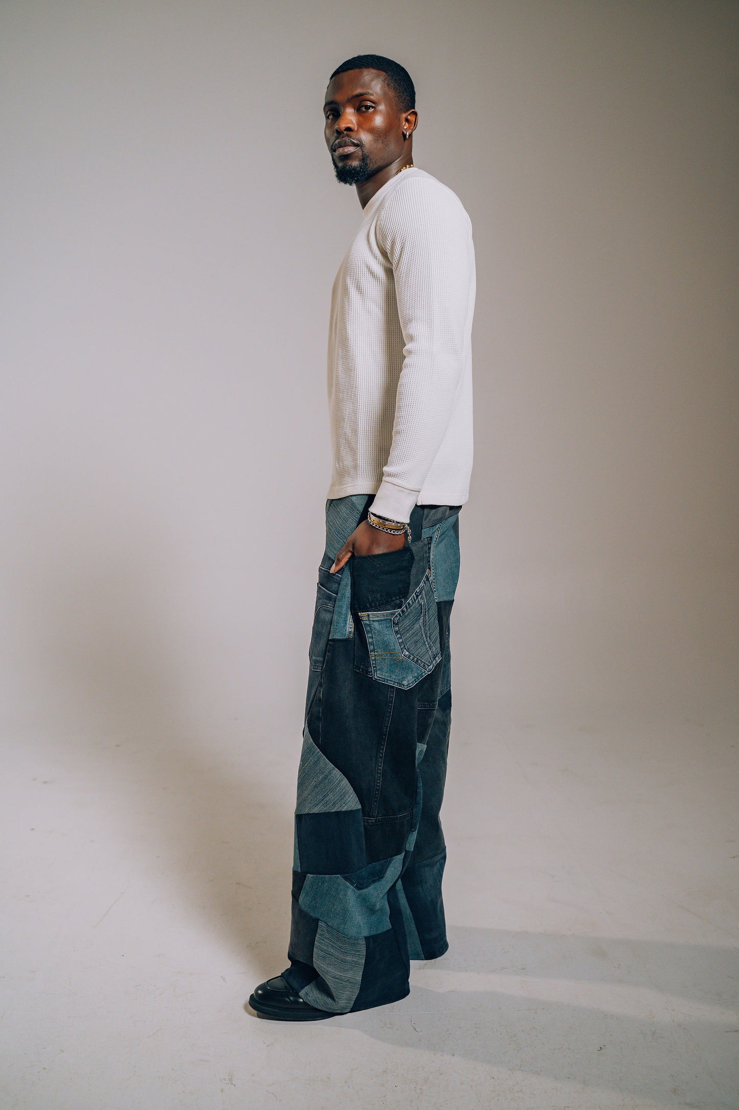 Man wearing a white long-sleeve shirt and patterned pants against a plain background