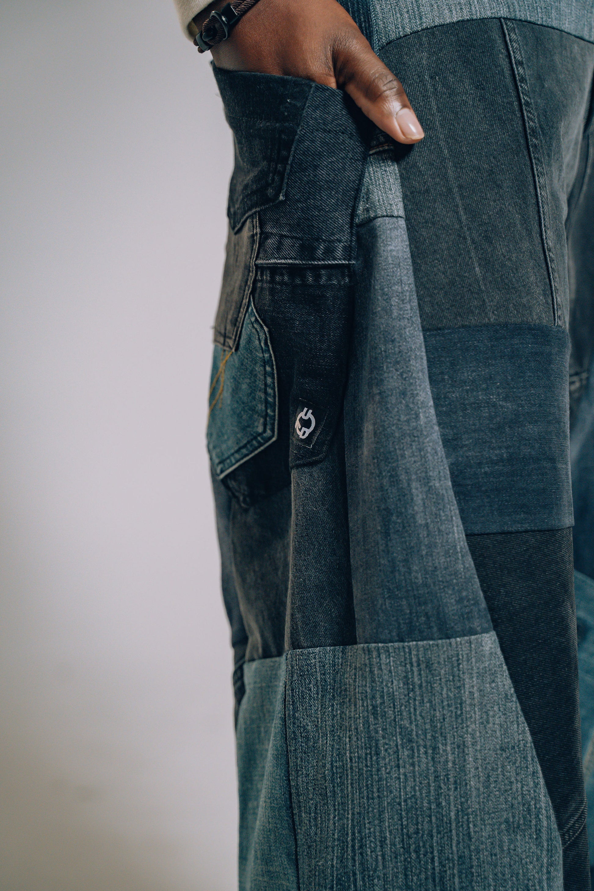 Close-up of a person wearing patchwork jeans with a neutral background
