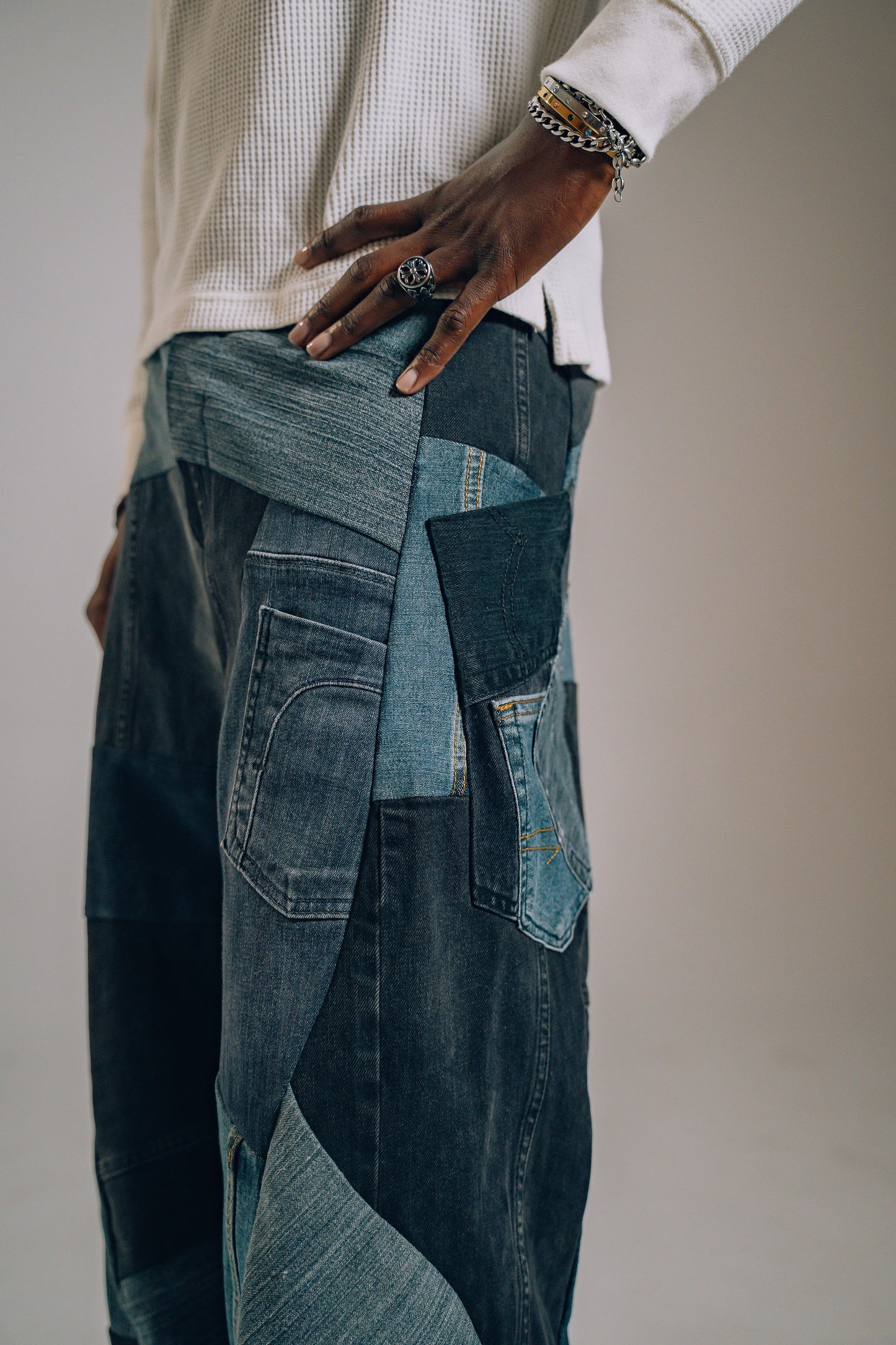 Person wearing a patchwork denim outfit with a neutral background