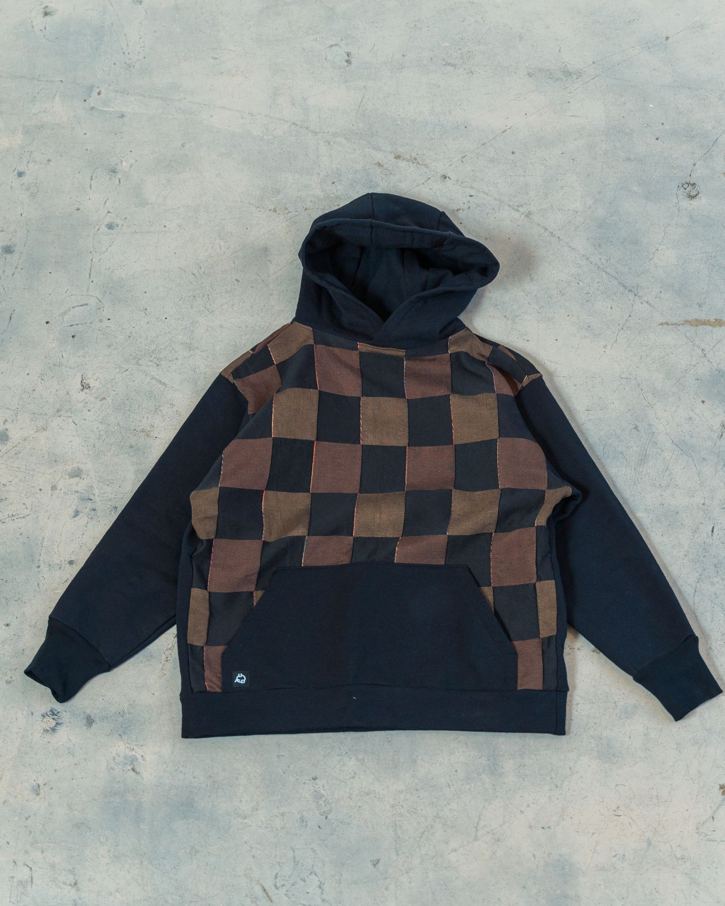 Checkered hoodie with black and brown pattern on a gray surface