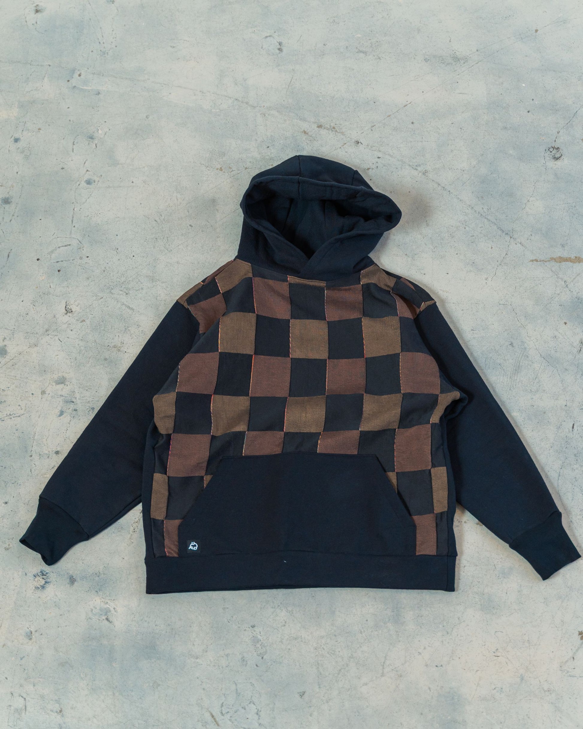 Checkered hoodie with black and brown pattern on a gray surface