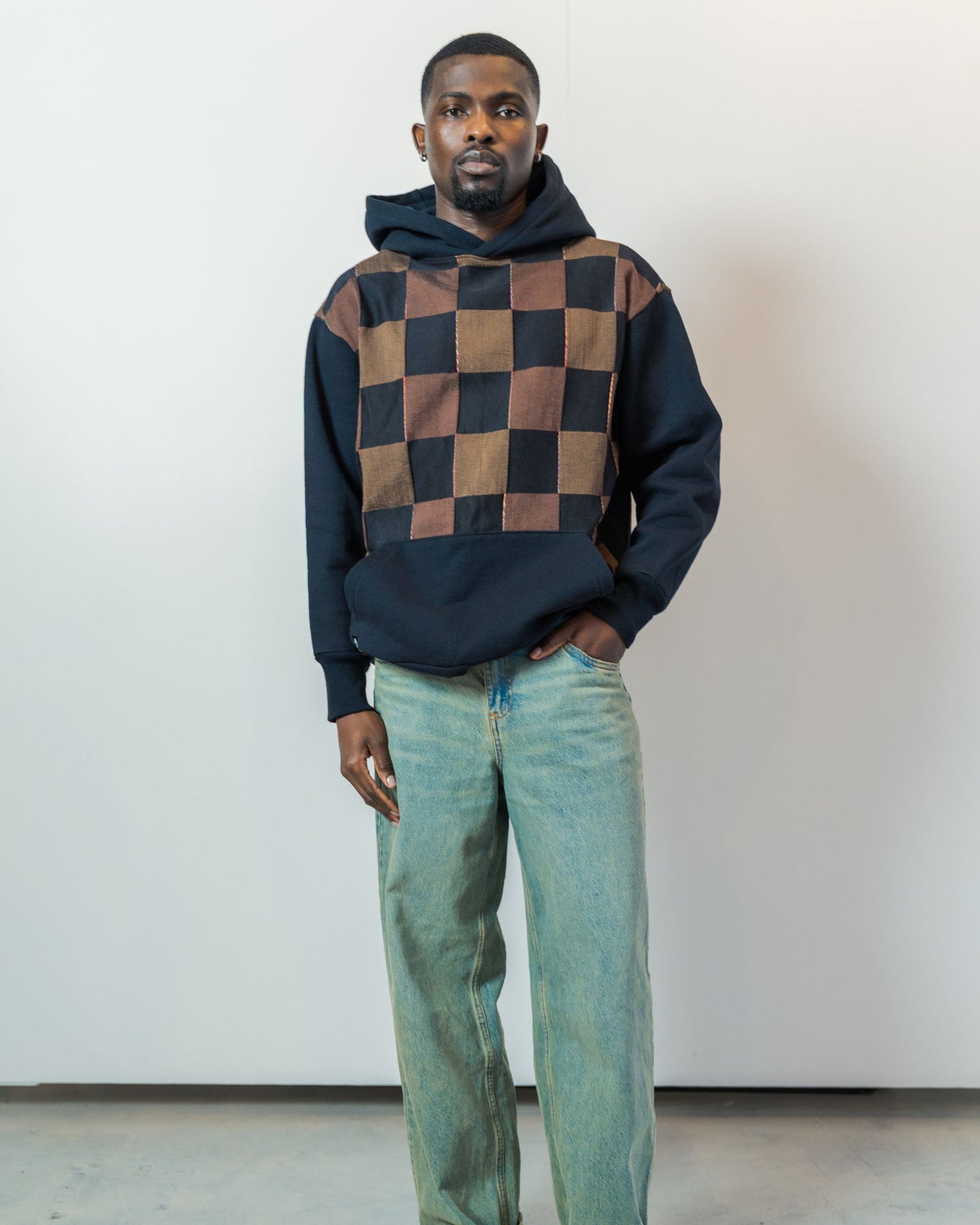 Person wearing a checkered hoodie and jeans against a plain background. Hoodie is made from upcycled vintage textiles.