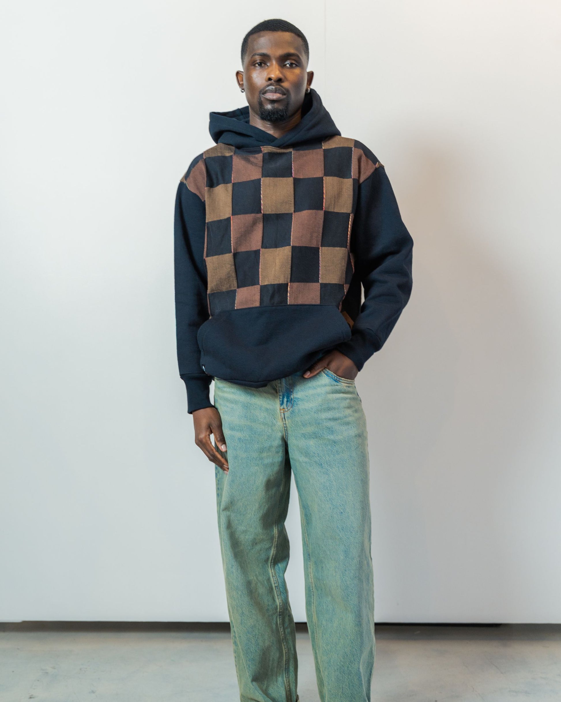 Person wearing a checkered hoodie and jeans against a plain background. Hoodie is made from upcycled vintage textiles.