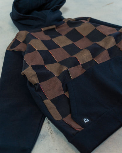 Hoodie on the ground showing stitchwork details and black and brown checkered fabric.