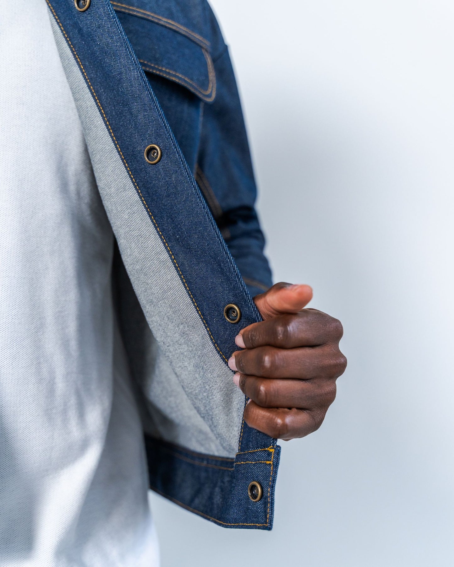 Person wearing a raw denim jacket showing the snaps with a blurred background