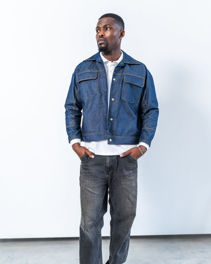 Man wearing a blue raw denim jacket and jeans against a white background